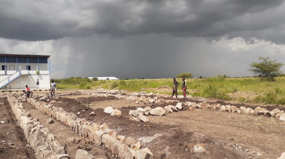 Construction site with workers under dark stormy skies.
