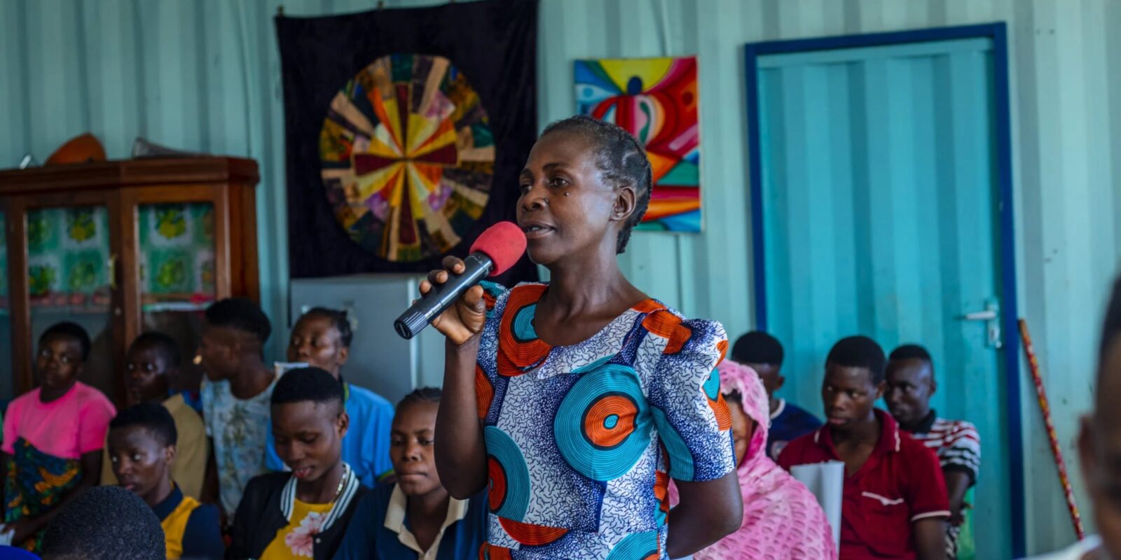 Woman speaking into a microphone in a community meeting.